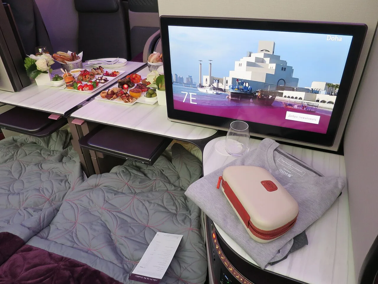 Qatar Airways Qsuite business class seat with closing privacy doors — the product flown on the MAN–DOH Airbus A350 route.