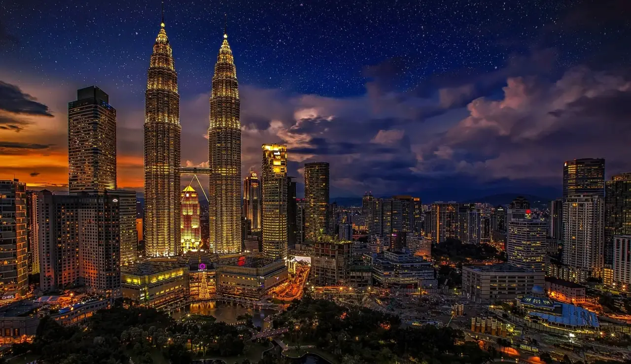Kuala Lumpur skyline at dusk with the Petronas Twin Towers lit against a deep blue sky